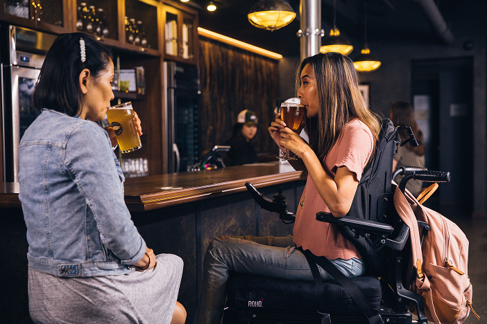 Two friends enjoying a drink together, one a wheelchair user